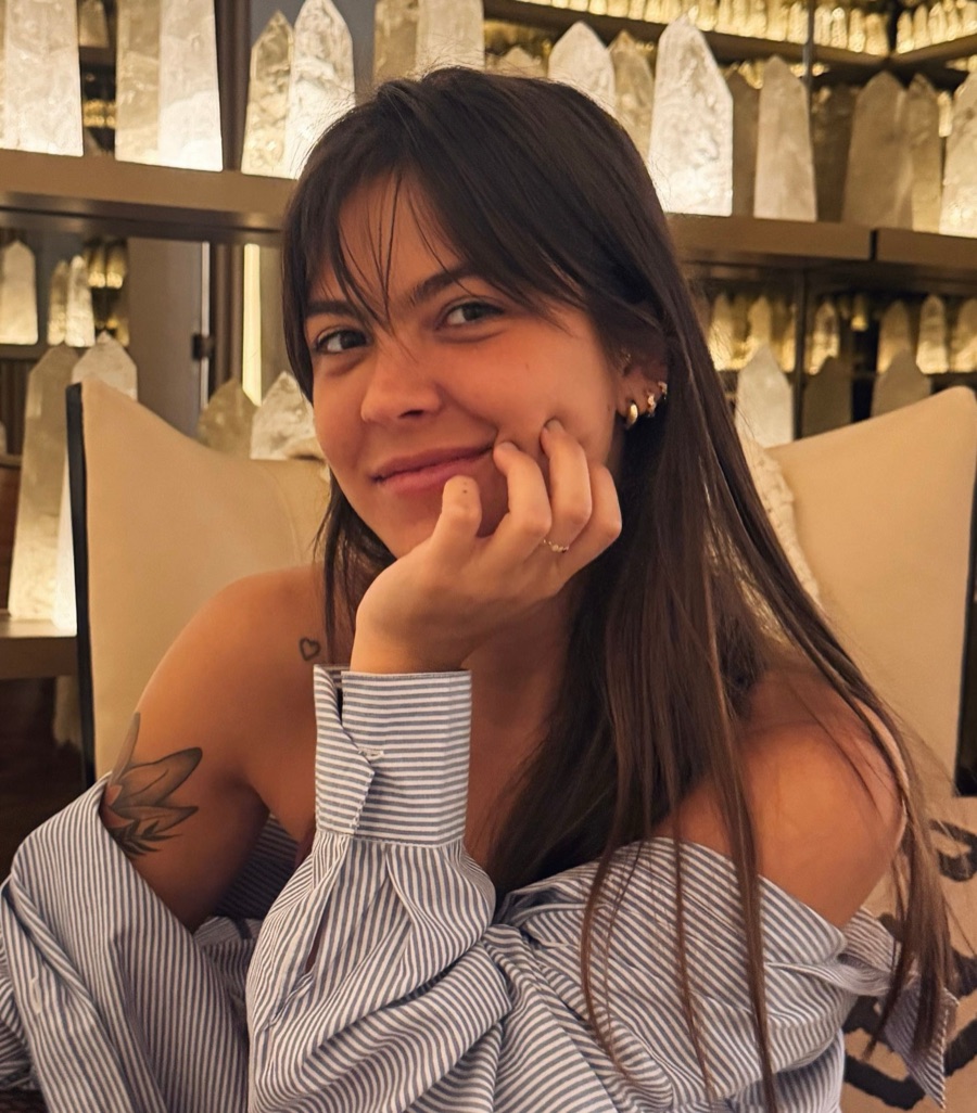 Isabelle Delamuta, psicóloga, sorrindo com a mão apoiada no rosto